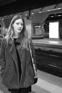 Portrait of beautiful woman standing at railroad station