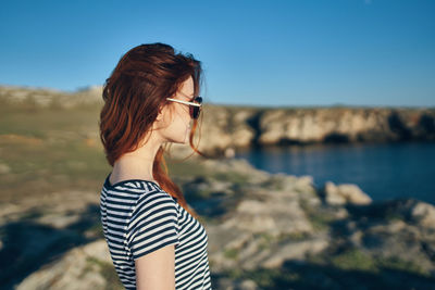 Young woman standing by sea against sky