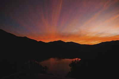 Scenic view of silhouette mountains against romantic sky at sunset