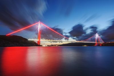 Illuminated suspension bridge over river at night