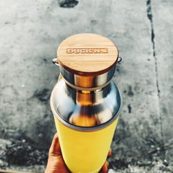 High angle view of hand holding glass bottle on table