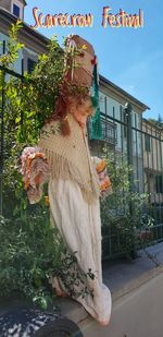 Midsection of woman holding plant against building