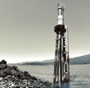 Lighthouse in sea against clear sky