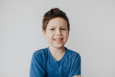 A preschool boy in a blue t-shirt on a light background shows a thumbs up. high quality photo