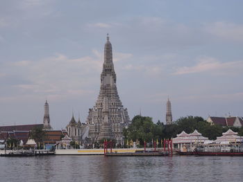 View of buildings by river against sky in city