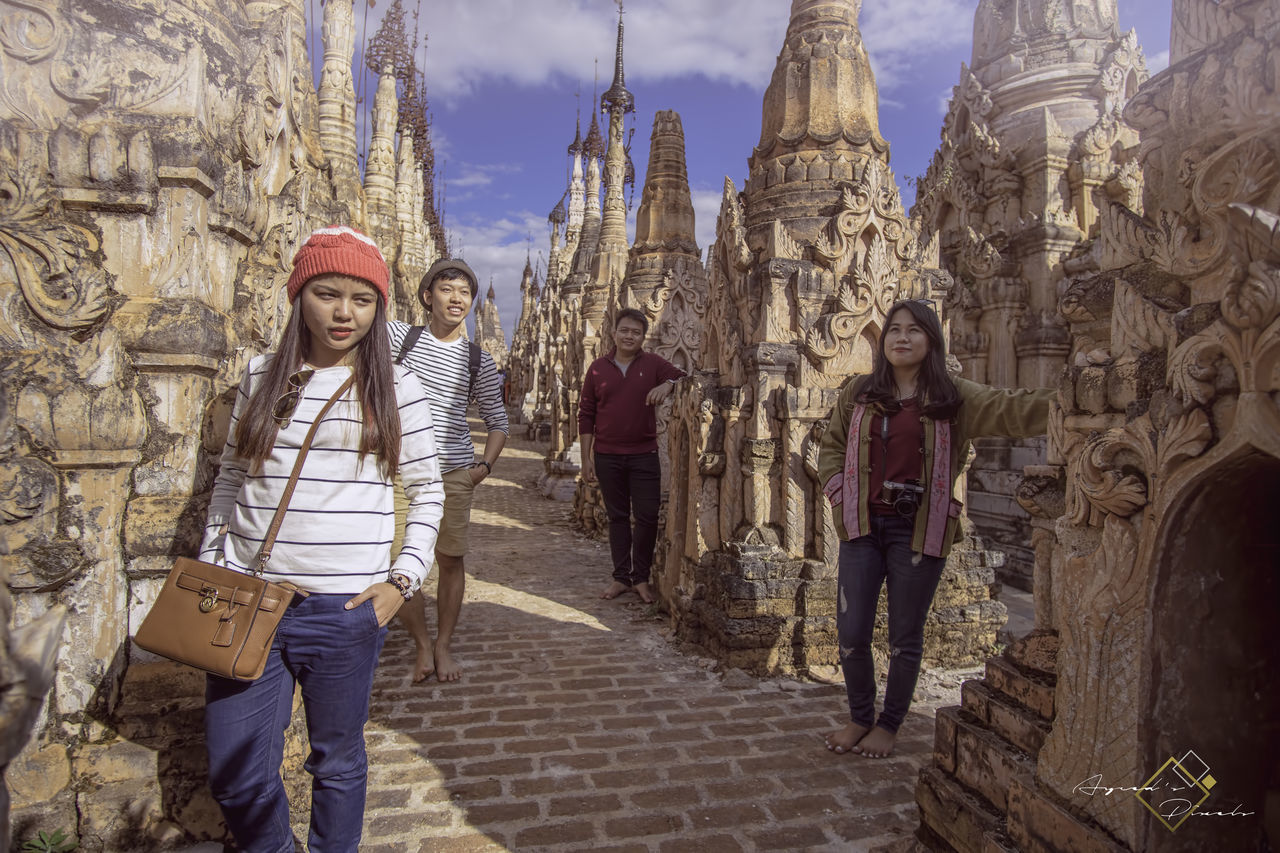 real people, front view, day, young women, young adult, smiling, looking at camera, built structure, outdoors, lifestyles, architecture, statue, building exterior, one person, sky, people