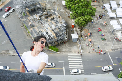 Caucasian woman wearing hero costume descending a tall building in rappel. 