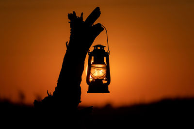 Lantern hanging on driftwood at sunset