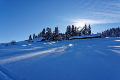 Snow covered landscape against blue sky