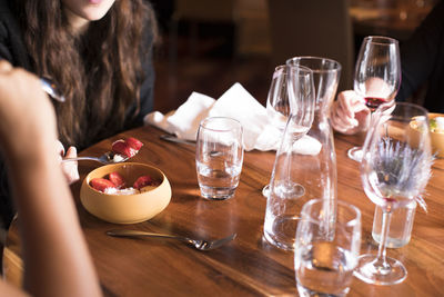 Midsection of woman with wine glasses on table finishing a meal