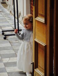 Smiling girl wearing white dress standing by doorway