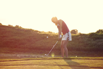 Man standing on golf course against sky