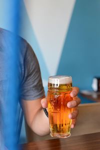 Midsection of man holding beer glass while sitting at table