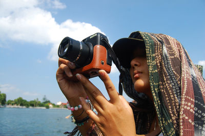 Woman photographing against sky