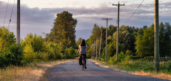 Rear view of man riding bicycle on road