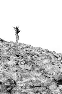 Man standing on rock against sky