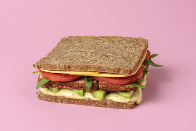 Vegan sandwich close-up on a pink table. wholemeal bread sandwich with vegan cheese, tofu, avocado.
