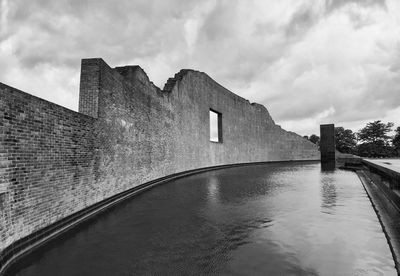 Building by river against cloudy sky