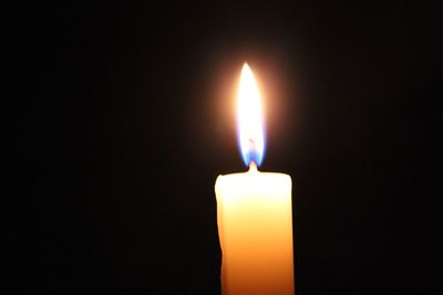 Close-up of lit candle in darkroom