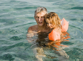 High angle view of grandfather with child swimming in pool