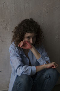 Portrait of young man sitting against wall