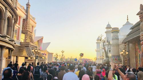 Group of people in front of buildings against sky in city