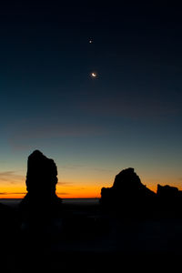 Silhouette of rocks against sky at dusk