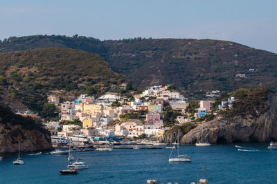 Sailboats in sea by townscape against sky