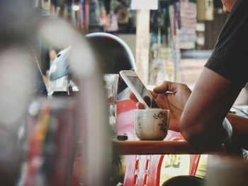 Cropped image of man using mobile phone at cafe