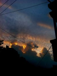 Low angle view of power lines against cloudy sky