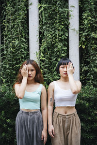 Portrait of beautiful young lesbian couple standing against plants outdoors