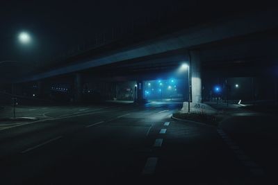 Empty road along illuminated buildings at night