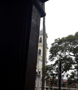 Low angle view of trees and building against sky