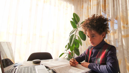 Rear view of boy looking at camera while sitting on table