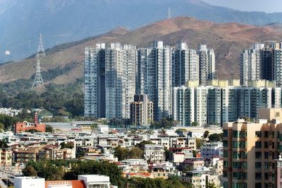 High angle view of residential buildings in city against sky and electricity towers. 