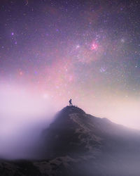 Silhouette person standing on mountain against sky at night