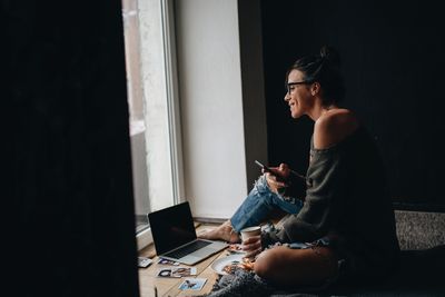 Woman using mobile phone while siting at home