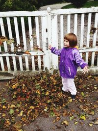 Full length of girl standing by railing during autumn