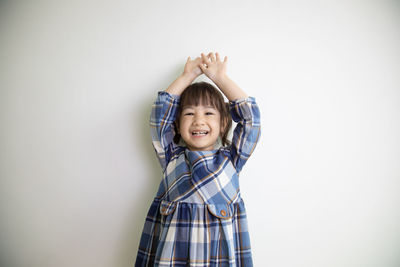 Portrait of a smiling girl standing against white background