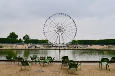 Ferris wheel by lake against sky