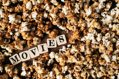 Close-up of movies text amidst popcorn on table