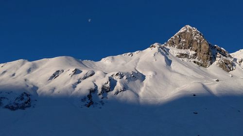 Scenic view of snowcapped mountains against clear blue sky