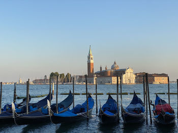 Boats moored in canal against clear sky