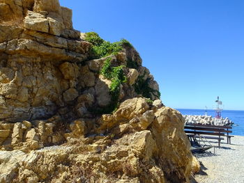 Cliff by sea against clear blue sky