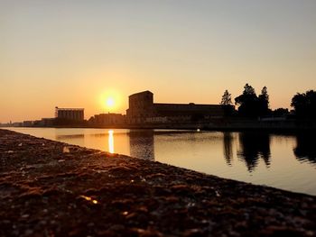 Scenic view of lake against clear sky during sunset in city