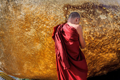 Rear view of monk standing by rock formation