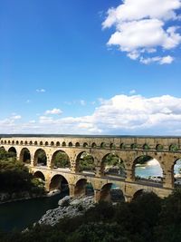 Arch bridge over river against blue sky