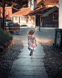 Rear view of woman walking on footpath by street