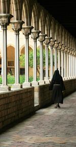 Full length rear view of nun walking in church corridor