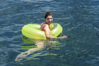 Woman in a bikini in the sea water with a buoy. 